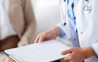 Female doctor holding application form while consulting patient