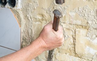 Worker removing tile with hammer and chisel