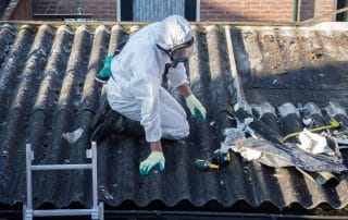 Men in protective suits are removing asbestos cement corrugated roofing