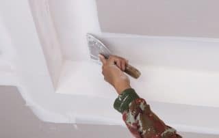 hand of worker using gypsum plaster ceiling joints at construction site