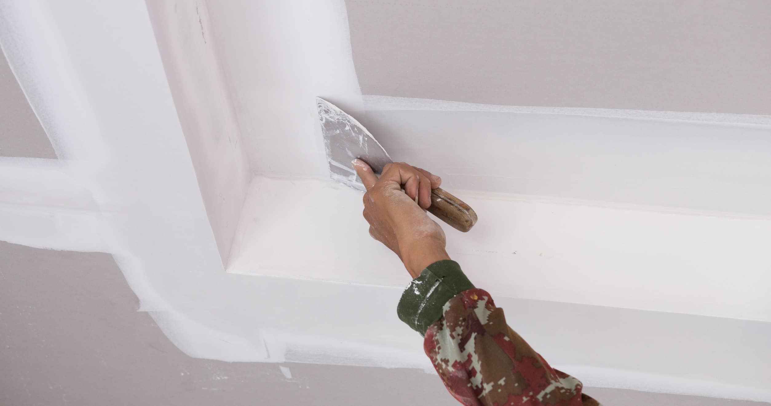 hand of worker using gypsum plaster ceiling joints at construction site
