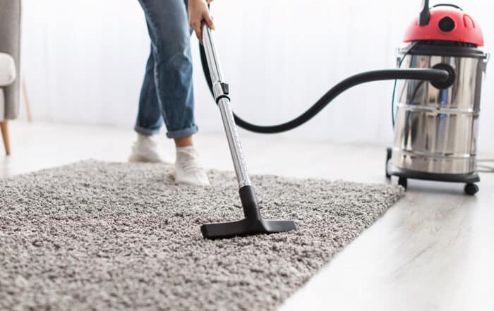 Woman vacuuming a rug in a living room